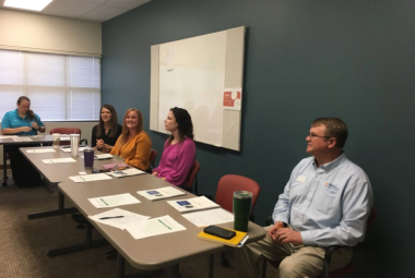 5 people sitting at a table engaging in training